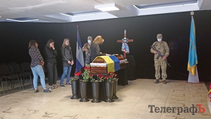 Дружина ніжно проводить рукою по закритій труні коханого