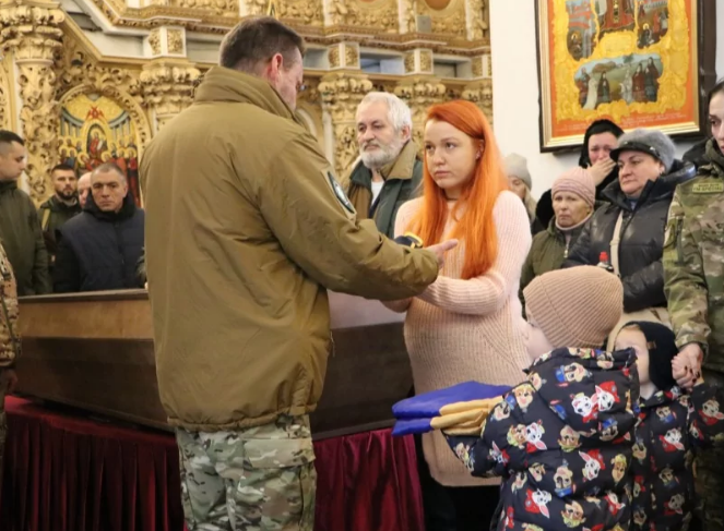 Вагітна дружина Олександра отримує стяг з рук військовослужбовців